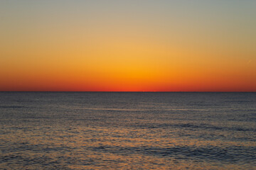 Beautiful sky with dark orange color after sunset over the sea. Georgia. Kobuleti