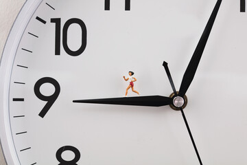 man running and exercising on the clock hand in miniature creative clock