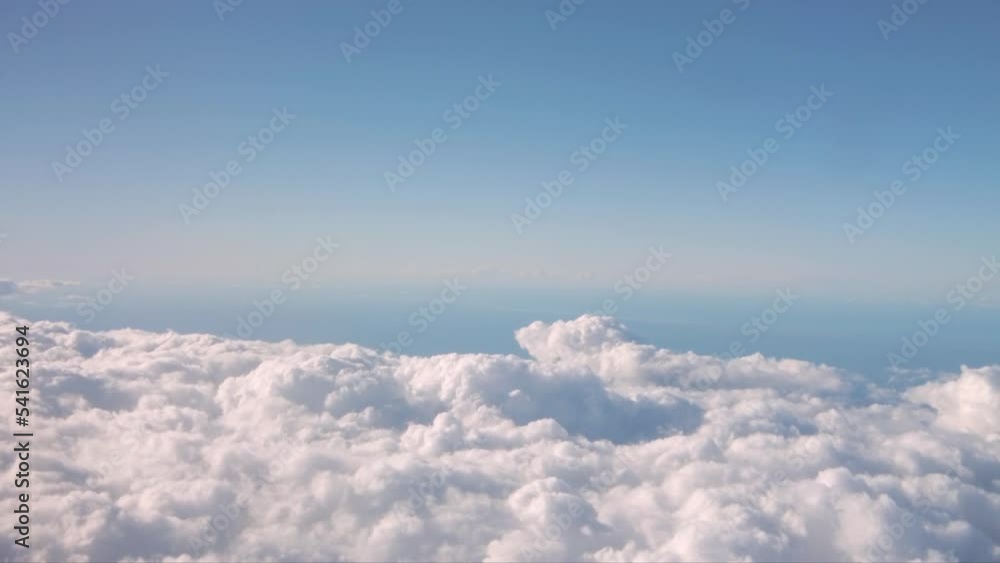 Poster motion shot from the window of an airplane with fluffy clouds beneath