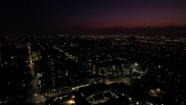 Aerial view of a residential neighborhood at night with a sunset almost ending in the background, drone shot.