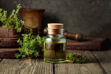 Bottle of thyme essential oil with fresh thyme twigs.