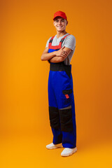 Full length shot of a young male worker in uniform on yellow background