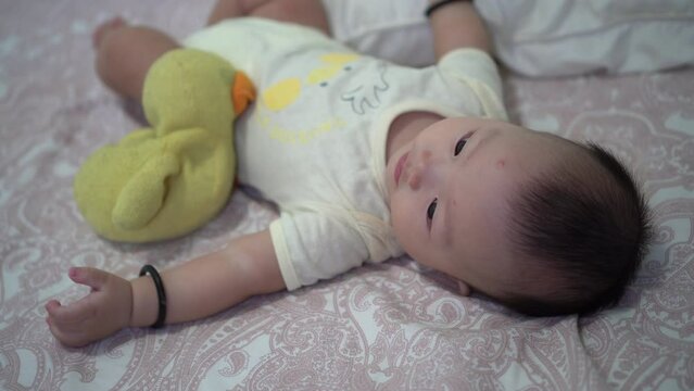Side view of cute baby with its old lovely yellow duck plush toy
