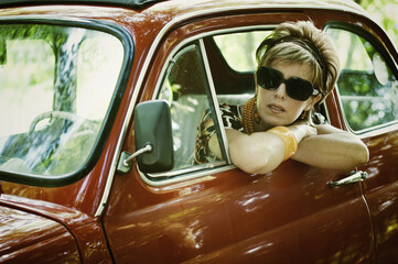 Naklejka premium Woman in 70's clothing in vintage car