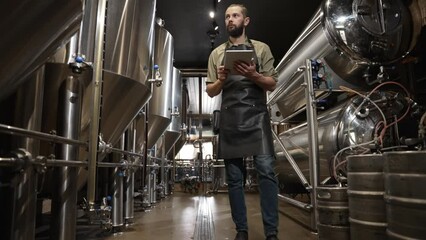 Brewer controls the production process brewing beer noting all the data tablet - Powered by Adobe