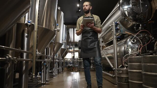 Brewer controls the production process brewing beer noting all the data tablet