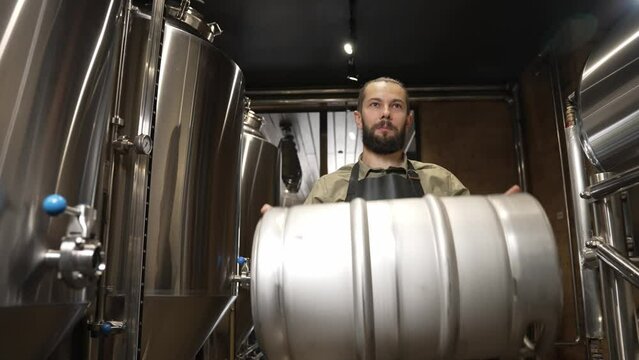 A working male brewer carries a barrel full of beer in front of him
