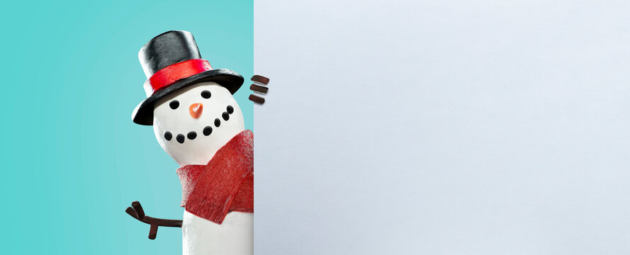 happy snowman behind a white sign - copy space