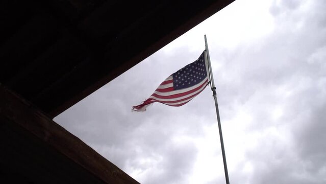 Worn and torn flag. American flag in a stiff breeze, flapping and tattered because of exposure