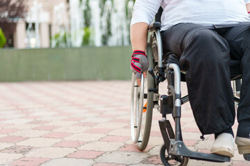 Obraz premium Unrecognizable woman with disability sitting in wheelchair in the street close up