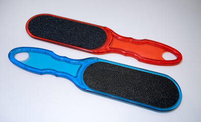 Plastic pedicure grater. Pyatkoterka made of blue and red plastic. Pedicure file on white isolate.