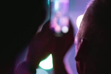 audience capture concert moment, hand holding blurred mobile phone as background