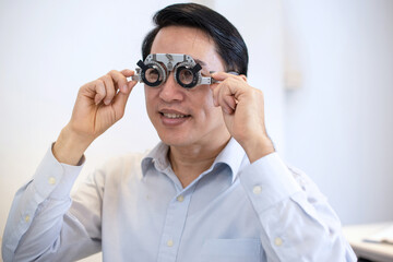 Asian man with optometrist trial frame, male patient to check vision in ophthalmological clinic