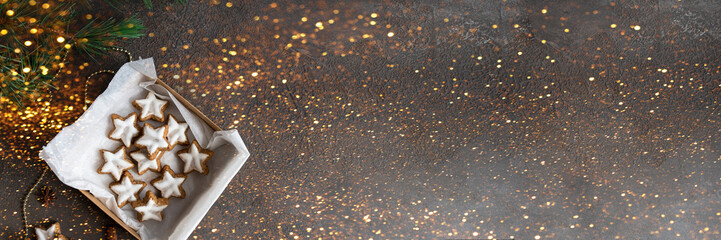 tar shape ginger cookies with sugar icing on white plate with XMAS letters and fur branch.