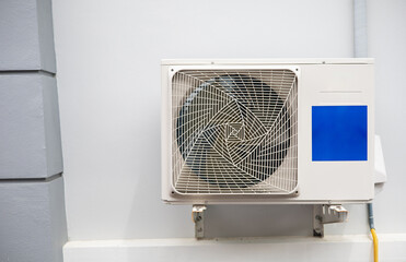 The air conditioner's cooler is mounted on the white wall of the house.