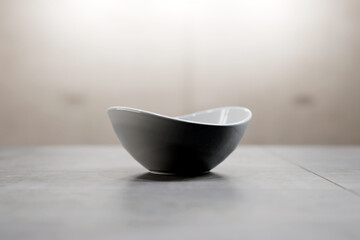 White empty porcelain cereal bowl on organic tile surface.
