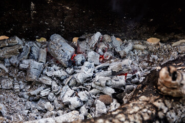 Smoldering charcoal in a barbecue. Scattered pieces of embers in the hearth mixed with ash. Ashes after to prepare food outdoor