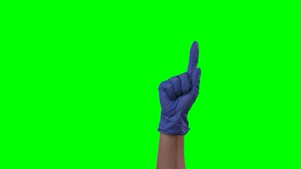 Woman hand in a medical blue glove pointing up with index finger at something. Doctor arm in protective glove showing copy space or presenting. Close up on green screen background.