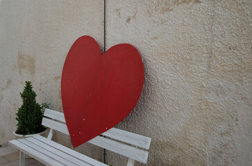 La sagoma di un cuore appoggiata su una panchina bianca in un vicolo di Castro, borgo del Salento in Puglia
