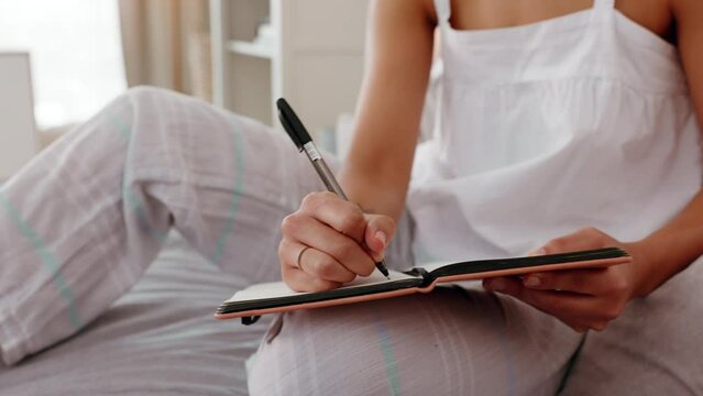 Woman writing in journal, hand notes in bedroom with pen and student learning education at home. Creative writer with notebook, planning schedule in morning routine and sitting on bed with diary page