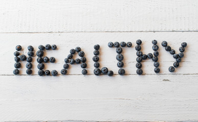 Berries on white background with text healthy written in blueberries