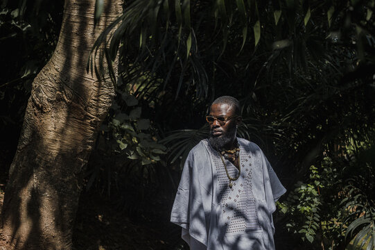 portrait of an african man in an agbada around palm trees