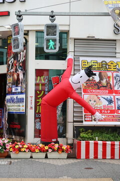 TOKYO, JAPAN - July 27, 2019: The front of a colorful modern Pachinko and Slot centre in Shimbashi in central Tokyo with a tube man outside.