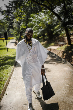 an african man in an agbada taking a walk in the park