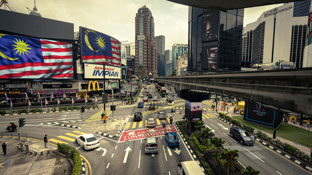Kuala Lumpur, Malaysia - August 21, 2022: Bukit Bintang intersection. Long exposure HDR image of the busy junction in KL city center. Cars and motorbike passing, the track of the monorail cross above.