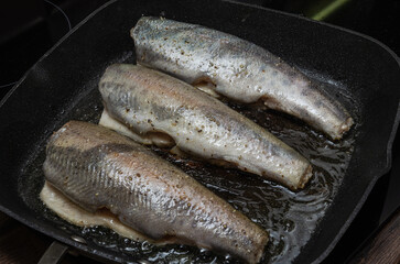 The cook fries rainbow trout fish in a pan