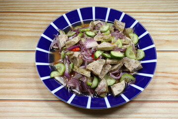 Spicy pork sausage salad mixed with sliced fresh shallot and cucumber serving on the plate. Famous appetizer menu in Asian restaurant. 