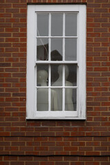 A white window frame with mannequins inside the building