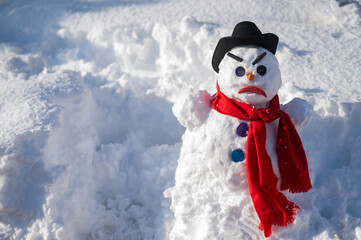 A snowman with a creepy grimace in a hat and scarf.