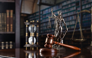 Fototapeta na wymiar Lawyer office. Judge’s gavel, scale, Themis sculpture and legal books in the bookshelf.
