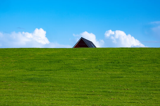 Ein Hausdach hinter einem Deich