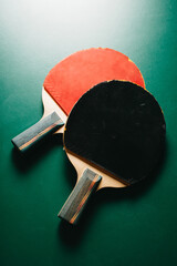 Two ping pong rackets are on the green game table