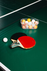 Two ping pong rackets and a ball are on the green game table