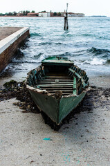 Una vecchia barca alla deriva portata a riva dalla corrente e arenata sullo scivolo di cemento...