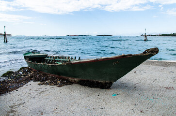 Una vecchia barca alla deriva portata a riva dalla corrente e arenata sullo scivolo di cemento...