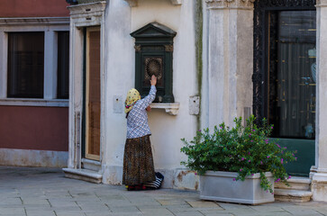 Una zingara prega davanti a un tabernacolo dedicato  alla madonna in una piazza di Venezia