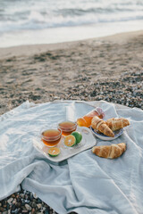 Tasty summer picnic with fresh tea and croissants on the beach at sunset.