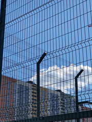 Fototapeta premium Residential building behind a mesh fence