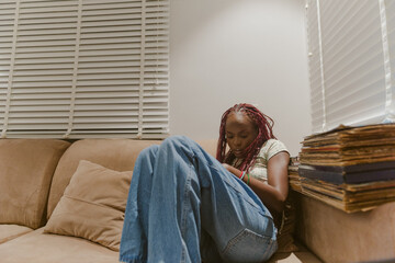 A black girl dressed comfy with braids cozied up on a couch