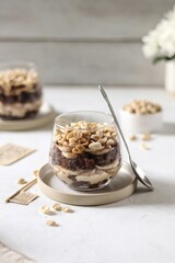 Dessert in glasses, chocolate biscuit with peanut cream, banana and nuts on the white background 