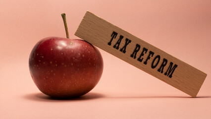 Tax Reform lettering on wooden surface. Apple pink background concept.