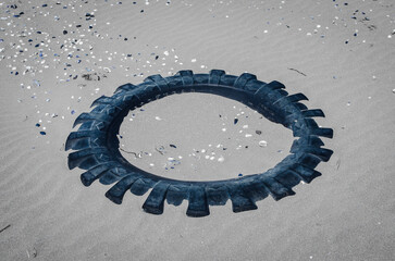 I resti di un copertone per la ruota di un camion abbandonato sulla spiaggia e sommerso dalla sabbia