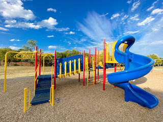 Colorful typical playground structure under sunny blue cloud sky at elementary school in Texas,...