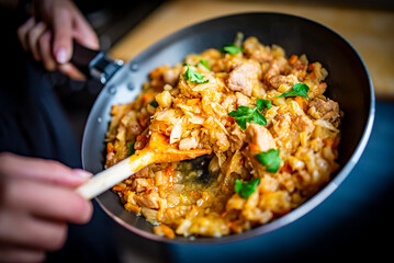Woman cooking tasty Stew with meat and cabbage in pan on kitchen