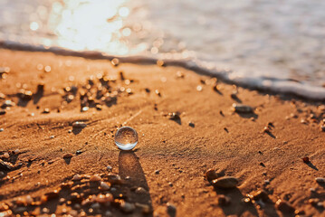 A crystal or glass ball on the sandy seashore in the sunset.