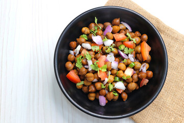 High in protine boiled black chana or chickpea salad. Chopped tomatoes, onion, chilies, and coriander mixed with boiled chickpea or Bengal gram. Weight loss meal. Served with Lemon. Copy space.